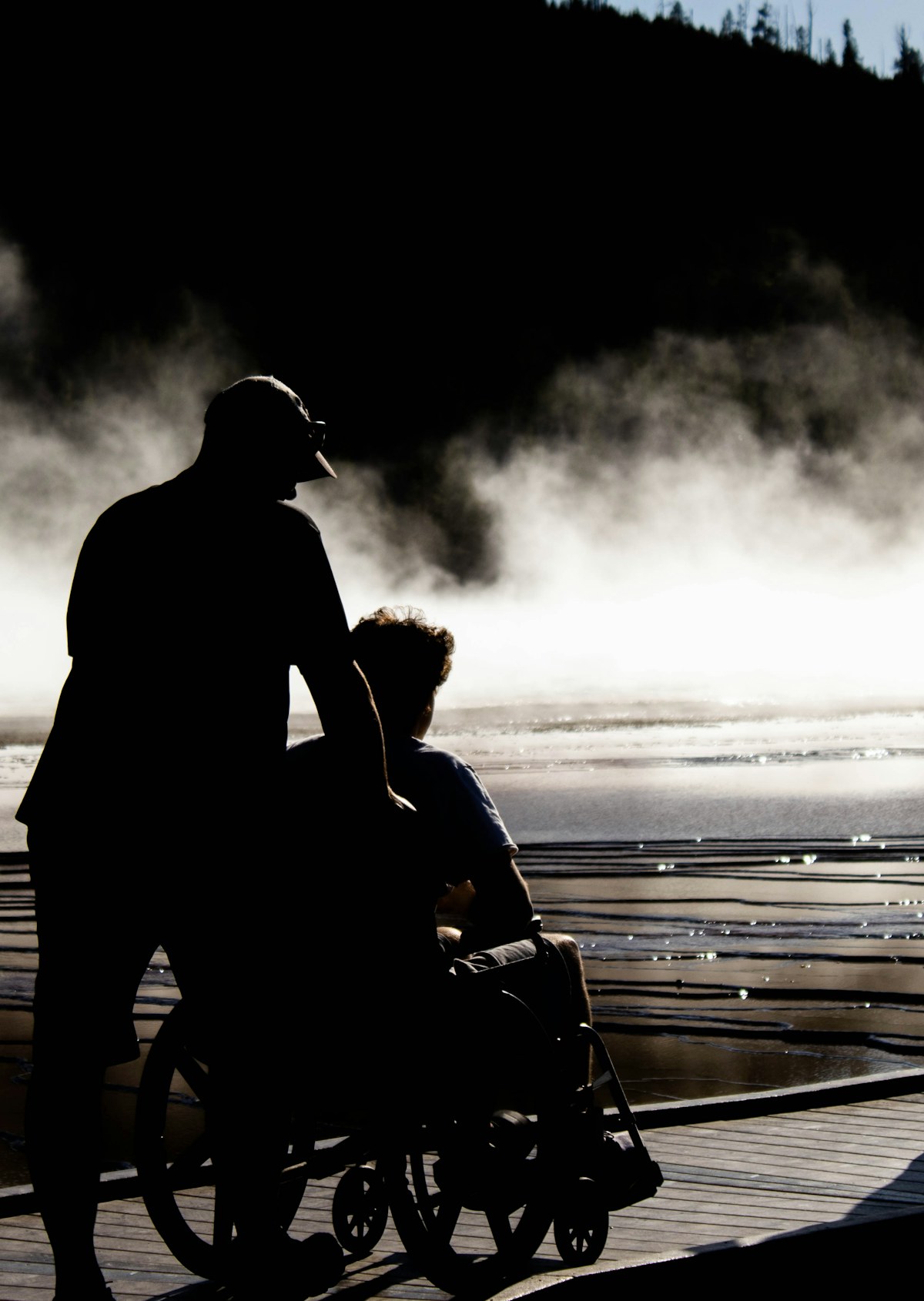 A caregiver supporting a wheelchair user at the seaside